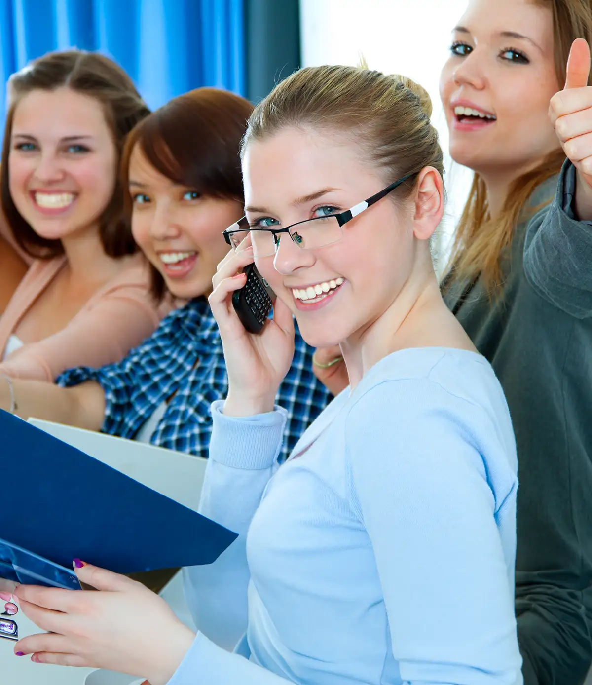 Gruppe unterschiedlicher Teenager, die in einer Beratungssitzung sitzen und sich in der Mitte an den Händen halten, um Teamwork und Unterstützung zu zeigen.