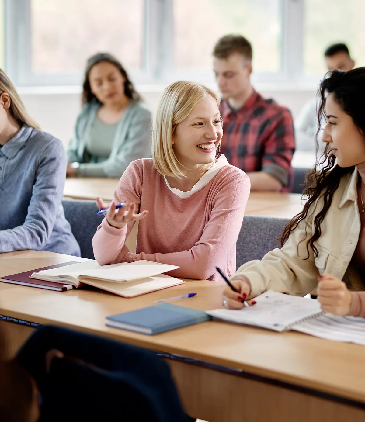 Glückliche Studentinnen unterhalten sich während einer Vorlesung an der Universität.